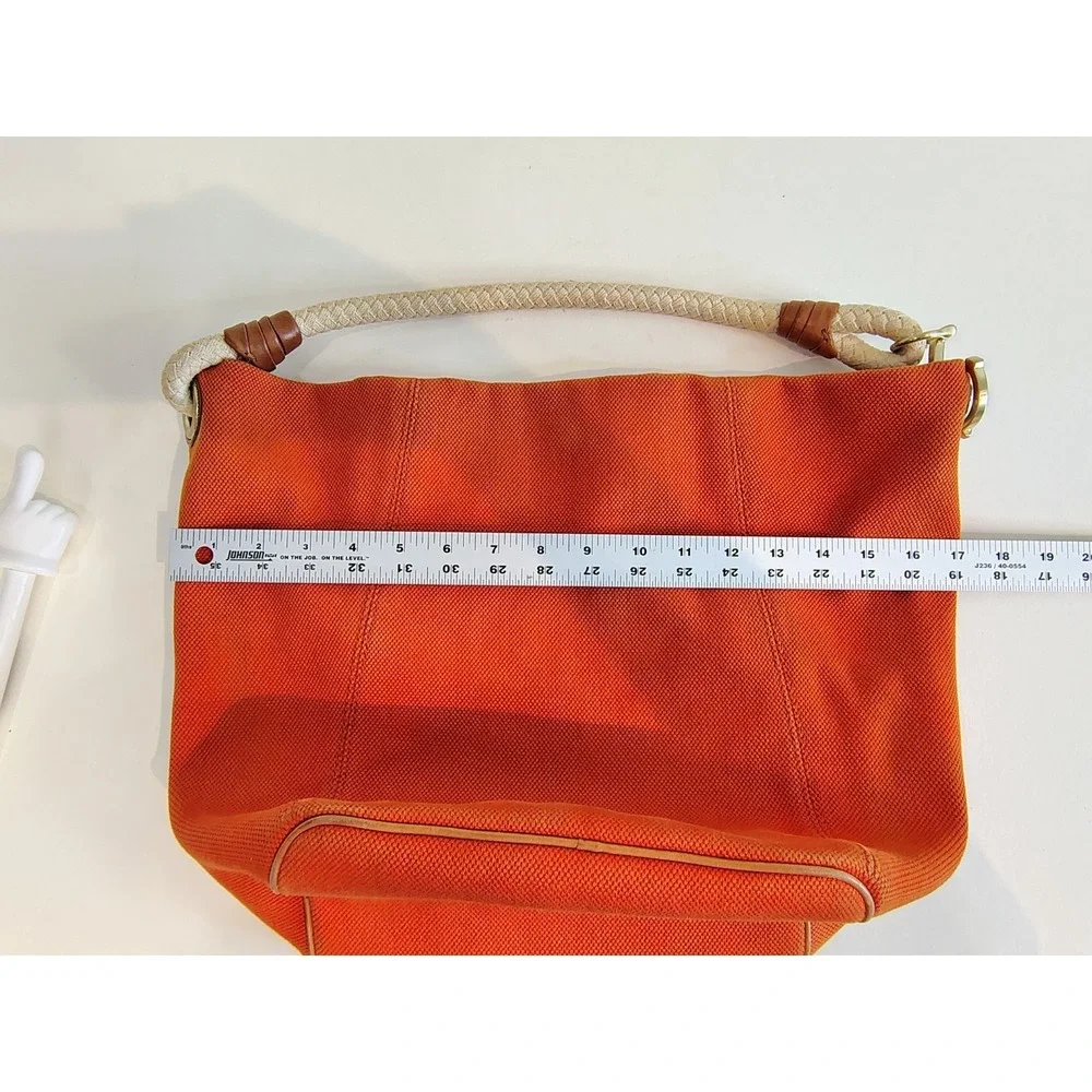 Michael Kors Marina hobo bag features an orange canvas body with braided rope...